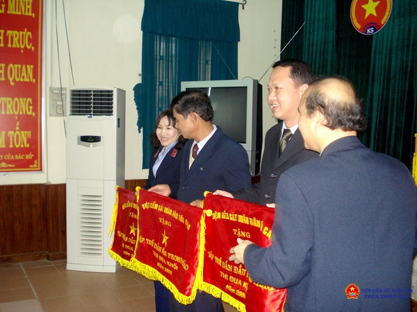 Đồng chí Nguyễn Văn A (người đứng giữa) nhận cờ Abc8 vin không bị chặn của Viện KSND tối cao tặng tập thể dẫn đầu phong trào Abc8 vin không bị chặn khối năm 2008. (một năm trước thời điểm nghỉ hưu)